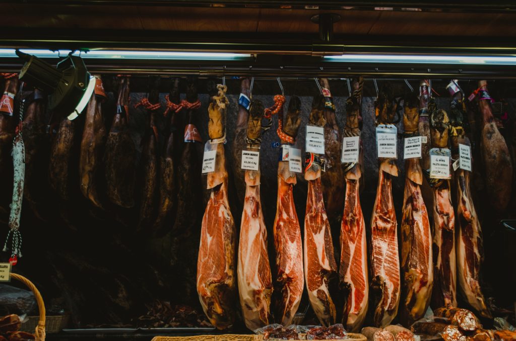 Vitrine d’une épicerie mettant en avant divers jambons ibériques.