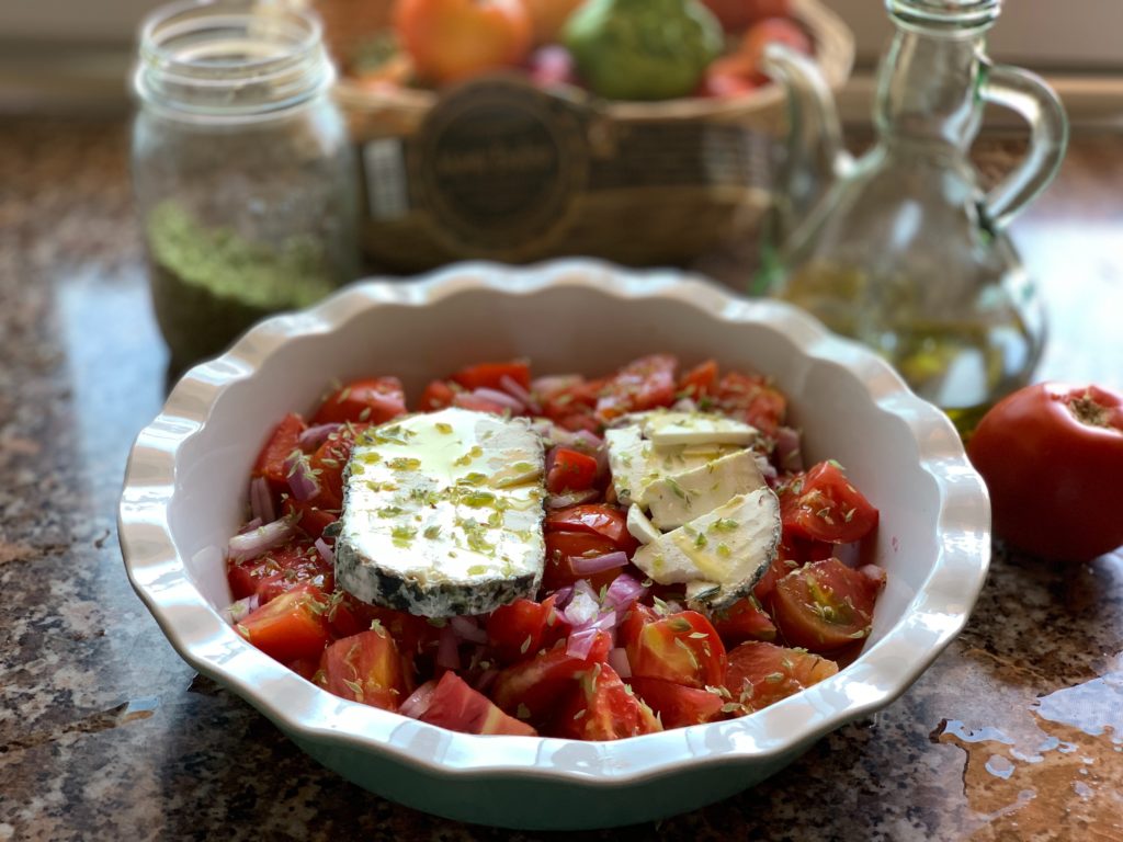 Salade de tomates avec un fromage de chèvre cendré sur le dessus.