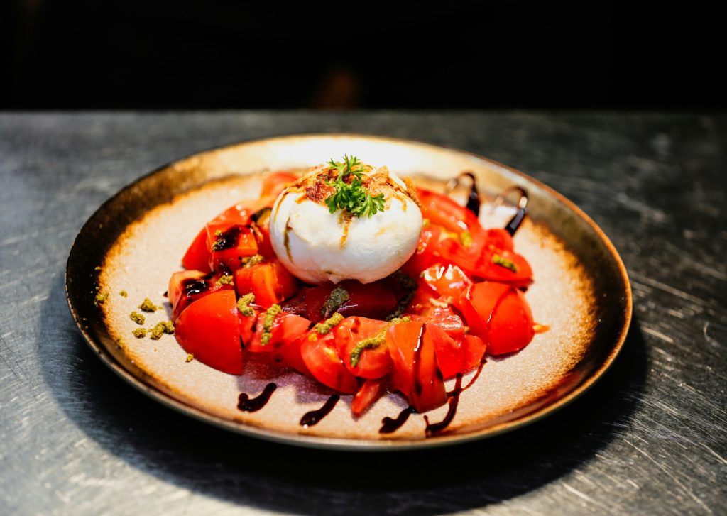 Recette fromages d’été: burrata crémeuse servie avec tomates fraîches et vinaigre balsamique, une entrée estivale gourmande.