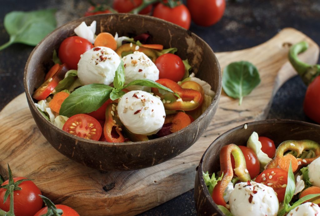 Mozzarella di bufala accompagnée de tomates cerises et de basilic, et de poivrons; une salade d’été classique avec un fromage d’été