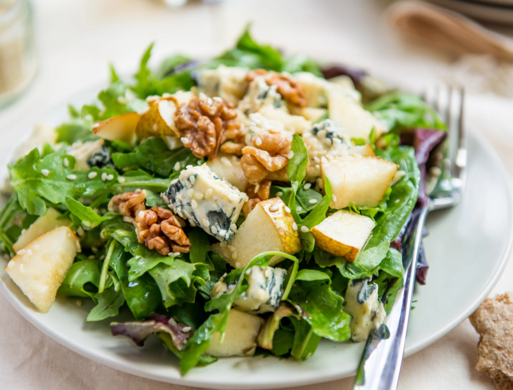 Salade automnale aux fromages bleus: ici, du roquefort, poires et noix sur assiette élégante