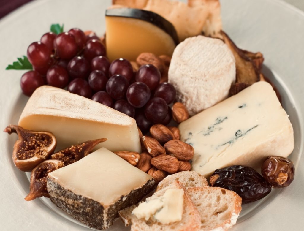 Assiette de fromages avec comme accompagnements pour le fromage du raisin, des figues séchées, dattes, noix…